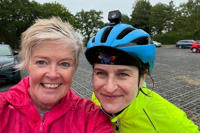 A photo of Christie Charity fundraisers Hayley Miller and Monika. Monika is wearing a bicycle helmet and both women are wearing rain jackets.