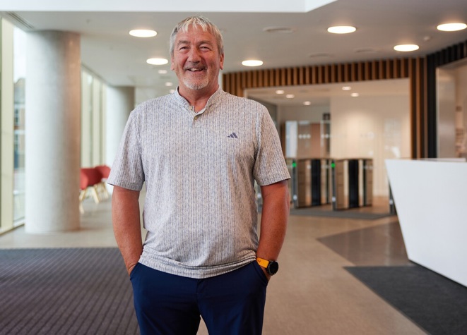 A photo of Christie patient Alan Traynor standing in the reception of the Paterson building.