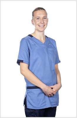 A photo of a registered nurse wearing a uniform in hospital blue with navy trim.