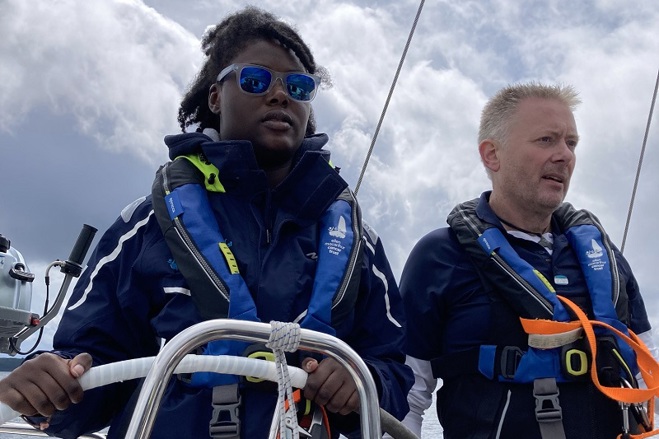 A photo of Christie patient Mercy wearing sunglasses and steering a boat.
