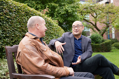 Two men on a bench talking