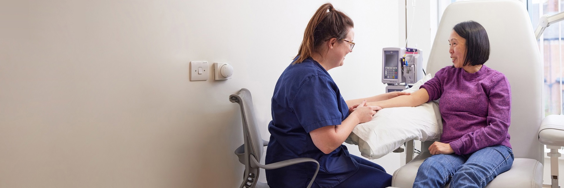A photo of a nurse treating a patient sitting in a chair.