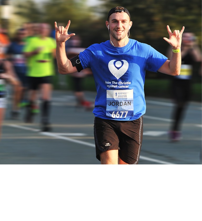 A photo of a man in a backwards baseball cap running and throwing his hands up in a rock sign; his T-shirt reads 'Join The Christie against cancer'.