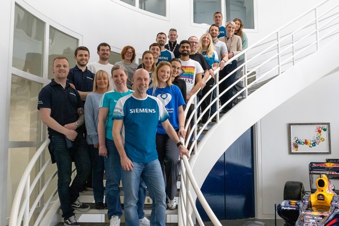 A photo of the 20 staff members from the team at Siemens in Manchester standing on a spiral staircase.