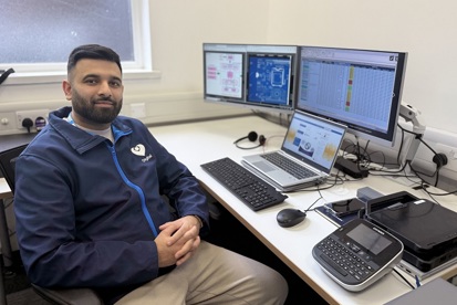 A photo of Aamir Hussain from The Christie IT team sitting in front of a computer screen.