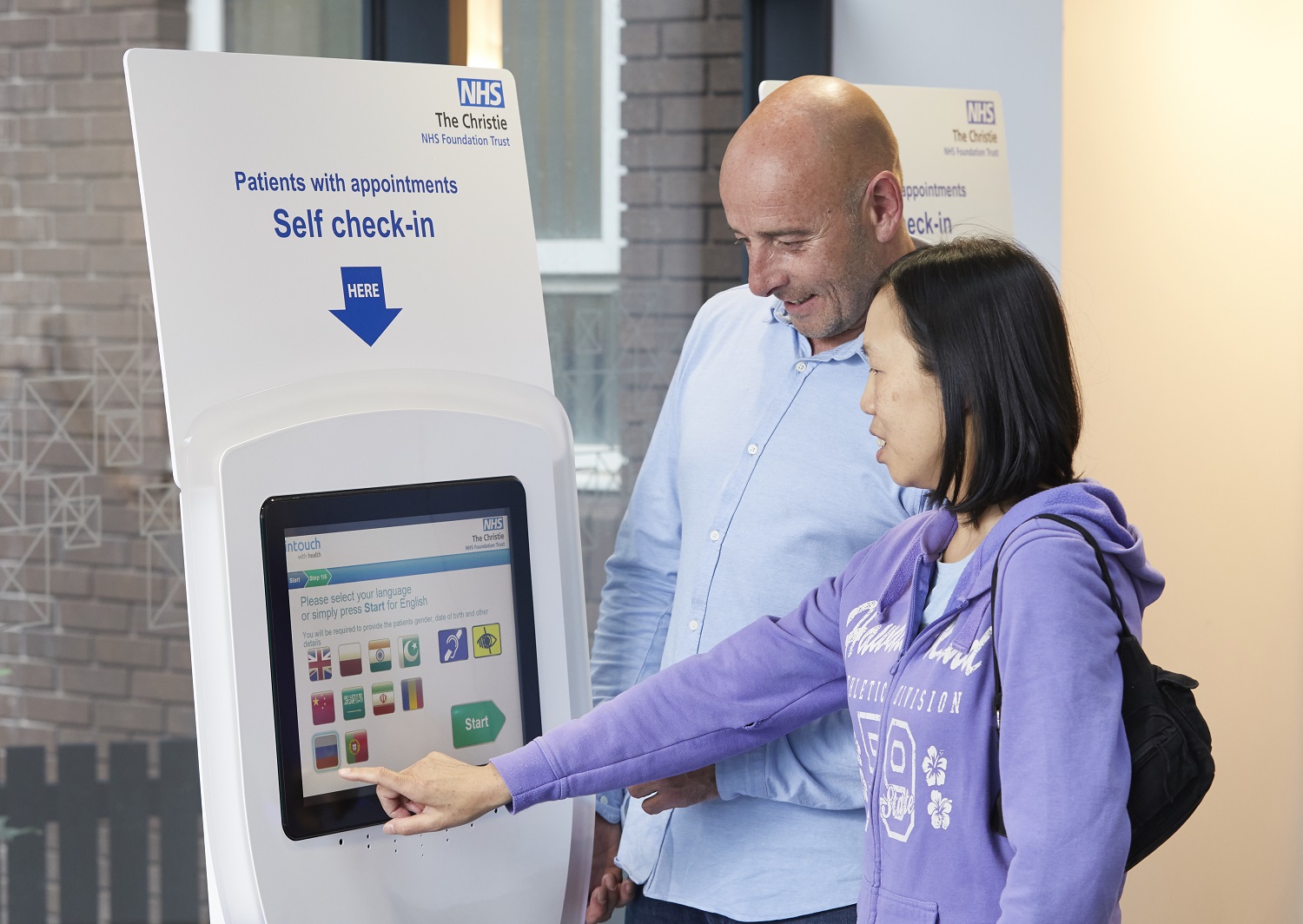 A photo of a man and a woman using the self-service check-in kiosk at The Christie's outpatients department.