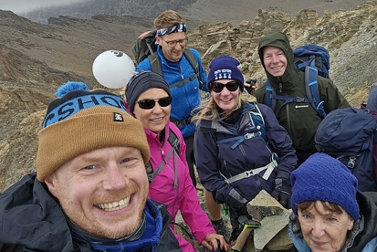 A photo of a group of trekkers on top of a mountain.