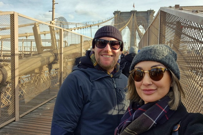 A photo of Paul and Jess Swift both wearing sunglasses and standing on a bridge.