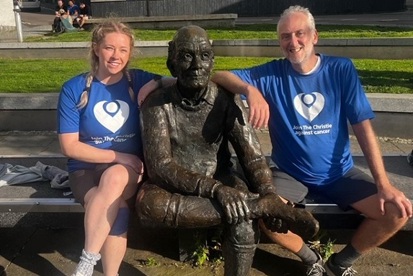A photo of Christie fundraiser Courtney Dobson sitting on a bench with her dad, Darren Walker and a statue.