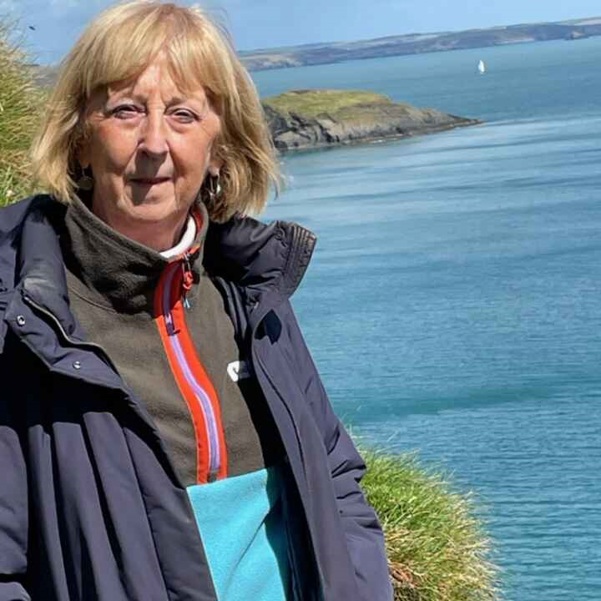 A photo of Christie patient Bernadette Smith standing on a cliff.
