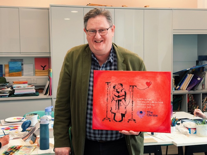 A photo of Christie prostate cancer patient, Paul King, posing with painting, Kissing Men.