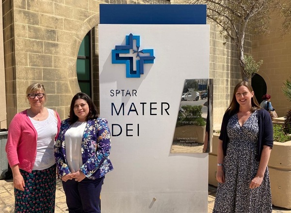 A photo of Julia Handley, Rachael Edwards and Dorothy Aquilina standing next to a MATER DEI Hospital sign in Malta.