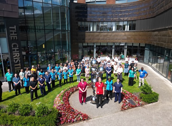 A photo of a large group of staff members standing outside the front of The Christie.