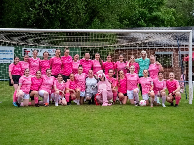 A photo of Meghan Glynn and the Worsley Wanderers FC women's football team wearing their pink football kit and standing in front of a goal.